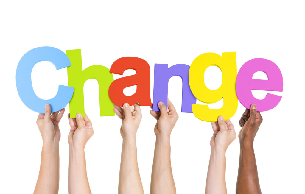 Hands holding up multi-coloured letters that make the word 'change'.